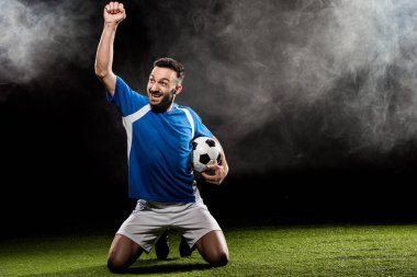zaferini kutluyor ve siyah duman ile topu tutan mutlu futbolcu