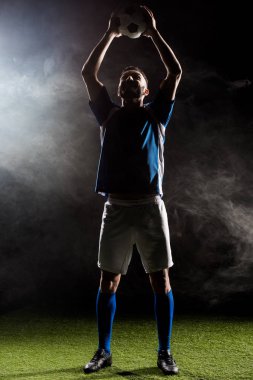 silhouette of football player holding ball above head on black with smoke   clipart