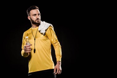 şişe su ile tutarak ve havlu üzerine siyah izole omuz ile ayakta yakışıklı teknik direktör