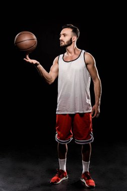 yakışıklı basketbol oyuncu dönen topa parmak siyah arka plan üzerine