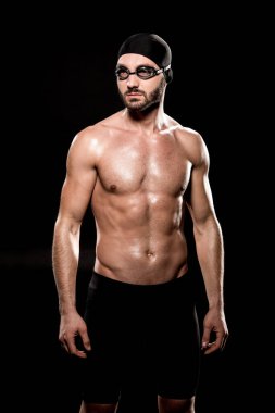serious swimmer standing in swimming cap and goggles isolated on black clipart