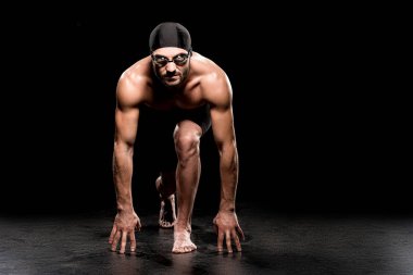 handsome swimmer standing in start position on black background  clipart