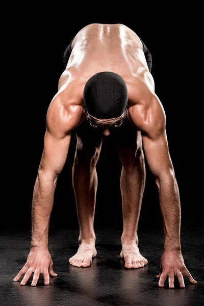 athletic sportsman standing in start position on black background