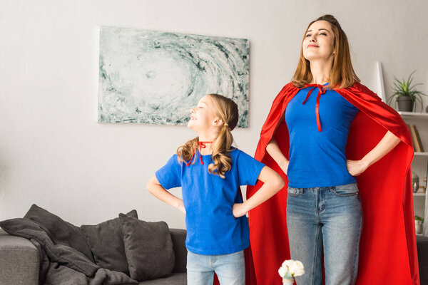 Mother and daughter in red cloaks looking away