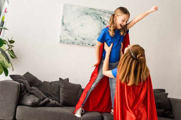 Kid and mother in red cloaks playing at home