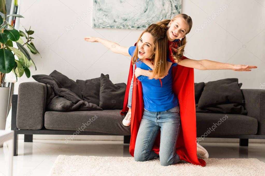 Cute kid and mother in red cloaks playing at home