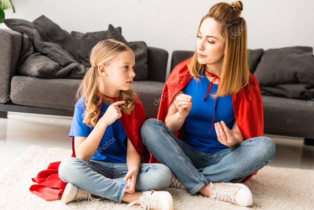 daughter and mother sitting on floor and talking at home