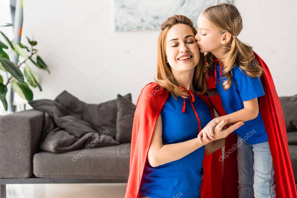 Cute daughter kissing and hugging mother at home 