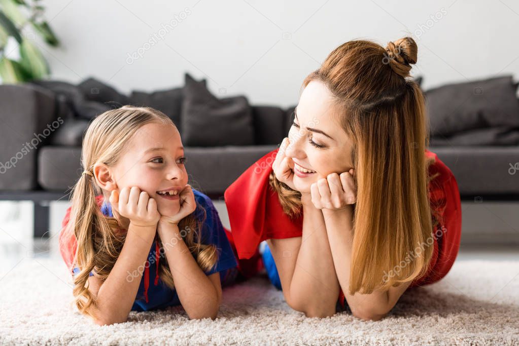 Smiling daughter and mother looking at each other on floor