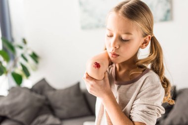 Üzgün çocuk evde yara üzerinde üfleme