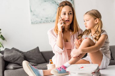 Üzgün anne Smartphone ve masada oturan yarayla evlat