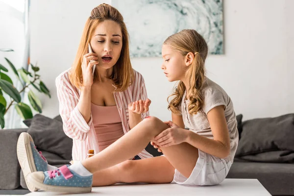 Madre Molesta Hablando Teléfono Inteligente Niño Con Herida Sentada Mesa — Foto de Stock