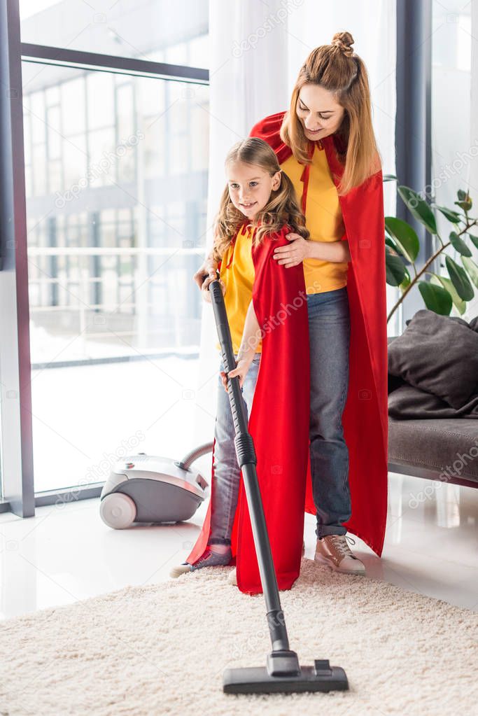 mother and kid in red capes with vacuum cleaner