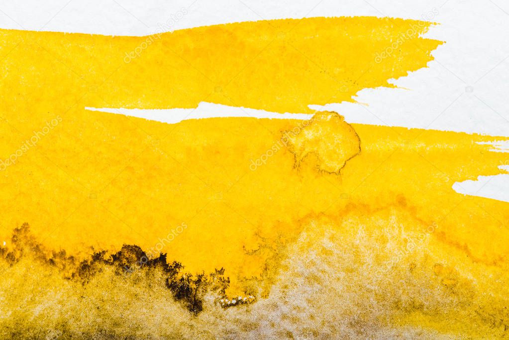 top view of yellow watercolor spill on white paper