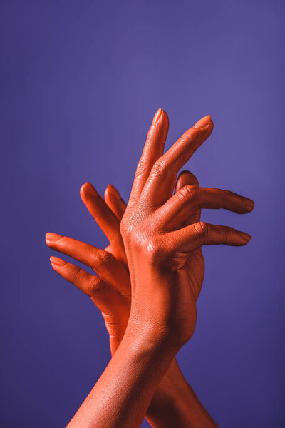 partial view of woman with coral colored hands on violet background,  color of 2019 concept