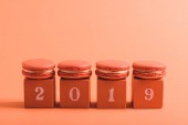 coral cubes with 2019 numbers and macarons on coral background, color of 2019 concept