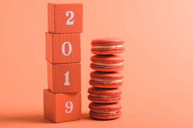2019 numaraları ve macarons mercan arka plan rengini 2019 kavramı üzerinde ahşap küpleri yığını