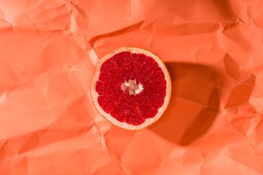 grapefruit half on crumpled paper textured coral surface, color of 2019 concept clipart