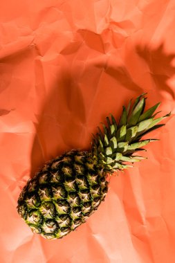 ripe pineapple fruit on on crumpled paper coral surface, color of 2019 concept clipart