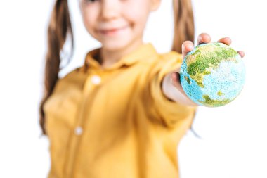selective focus of smiling kid with globe model in stretched hand isolated on white, earth day concept clipart