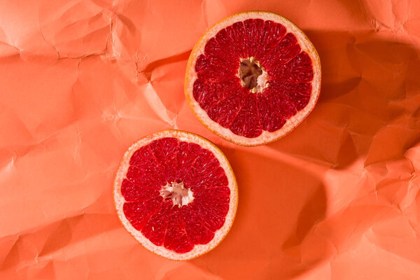 grapefruit halves on crumpled paper textured coral surface, color of 2019 concept
