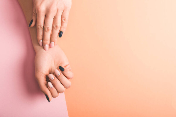 partial view of female hands with pink and black nails on bicolor background, color of 2019 concept