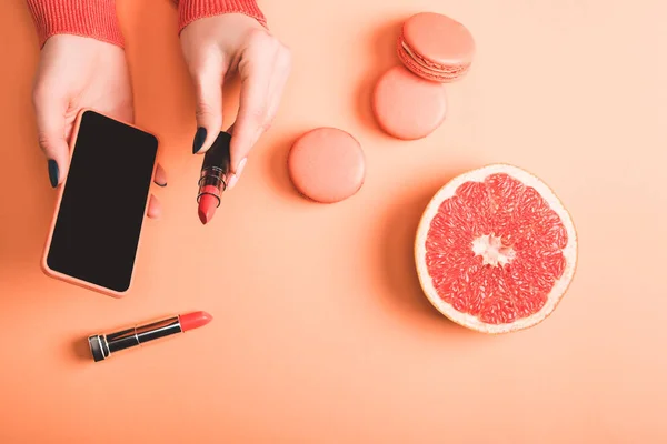 Cropped View Woman Holding Smartphone Coral Lipstick Macarons Grapefruit Half — Stock Photo, Image
