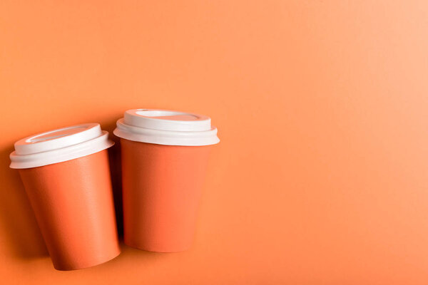 disposable cups on coral background, color of 2019 concept