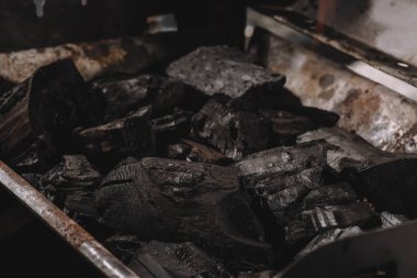 pile of dark black coals in iron barbecue  clipart