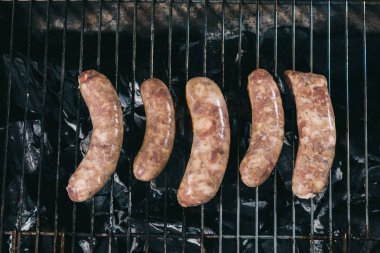 top view of raw fresh sausages preparing on barbecue grill grate clipart