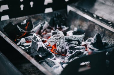 selective focus of hot burning coals with ash in iron bbq grill clipart