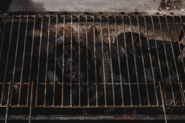 dark black natural coals under iron bbq grid