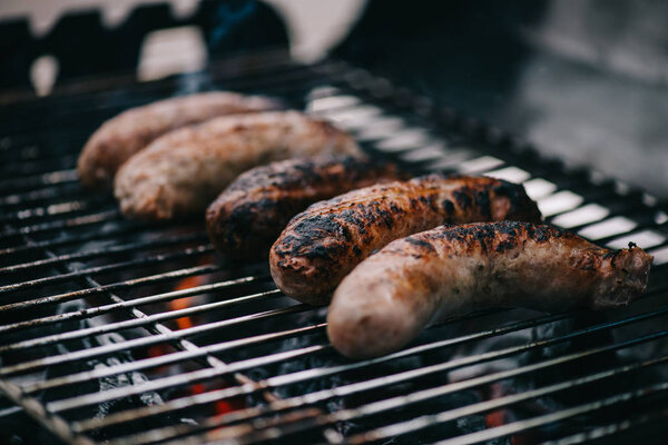 grilled tasty brown meat sausages on barbecue grid