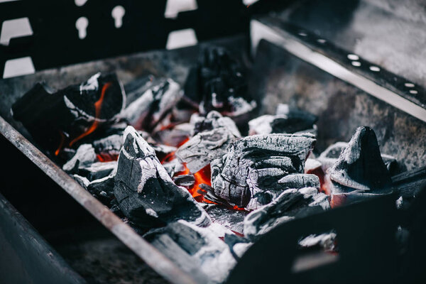 selective focus of hot burning coals with ash in iron bbq grill