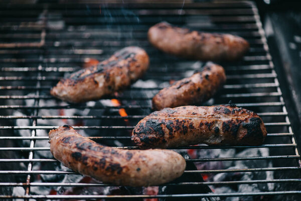 selective focus of grilled scattered delicious sausages on bbq grid