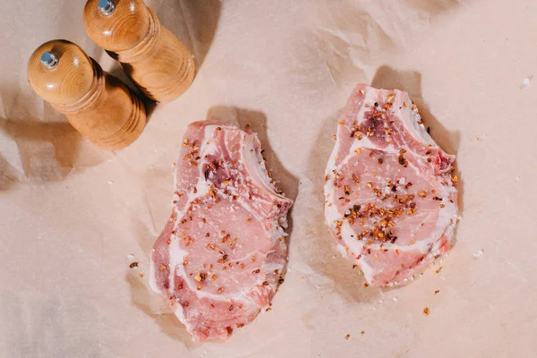 Draufsicht Auf Rohe Frische Steaks Mit Gewürzen Auf Papier — Stockfoto