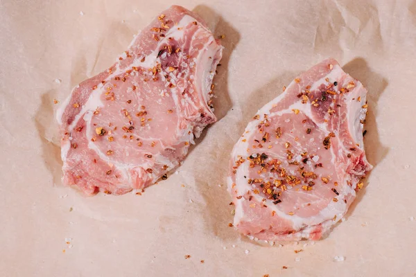 Draufsicht Auf Rohe Frische Steaks Mit Gewürzen Auf Papier — Stockfoto