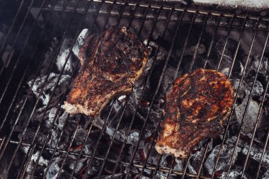 juicy steaks with crust grilling on hot coals with smoke clipart