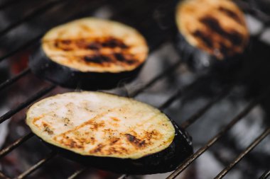 selective focus of eggplant slices grilling on barbecue grid clipart