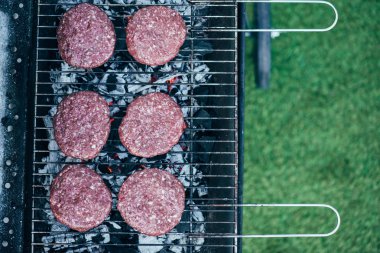 top view of uncooked fresh burger cutlets grilling on bbq grid clipart