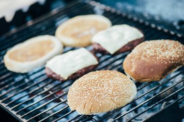 selective focus of delicious fresh burgers ingredients grilling on barbecue grid clipart