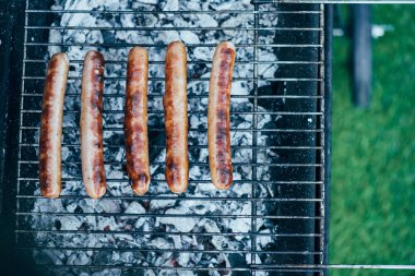 top view of tasty grilled sausages on bbq grill grade on green grass background clipart