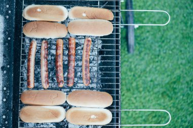 top view of tasty hot dogs grilling on bbq grill grade on green grass background clipart