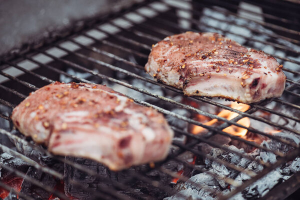selective focus of juicy raw steaks grilling on barbecue grid