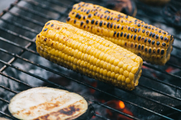 селективное фокусирование желтой кукурузы с коркой и баклажанами на гриле на решетке барбекю
