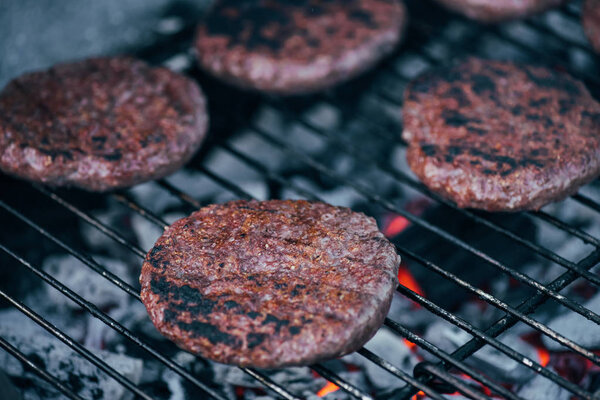 selective focus of grilled fresh burger cutlets on bbq grid