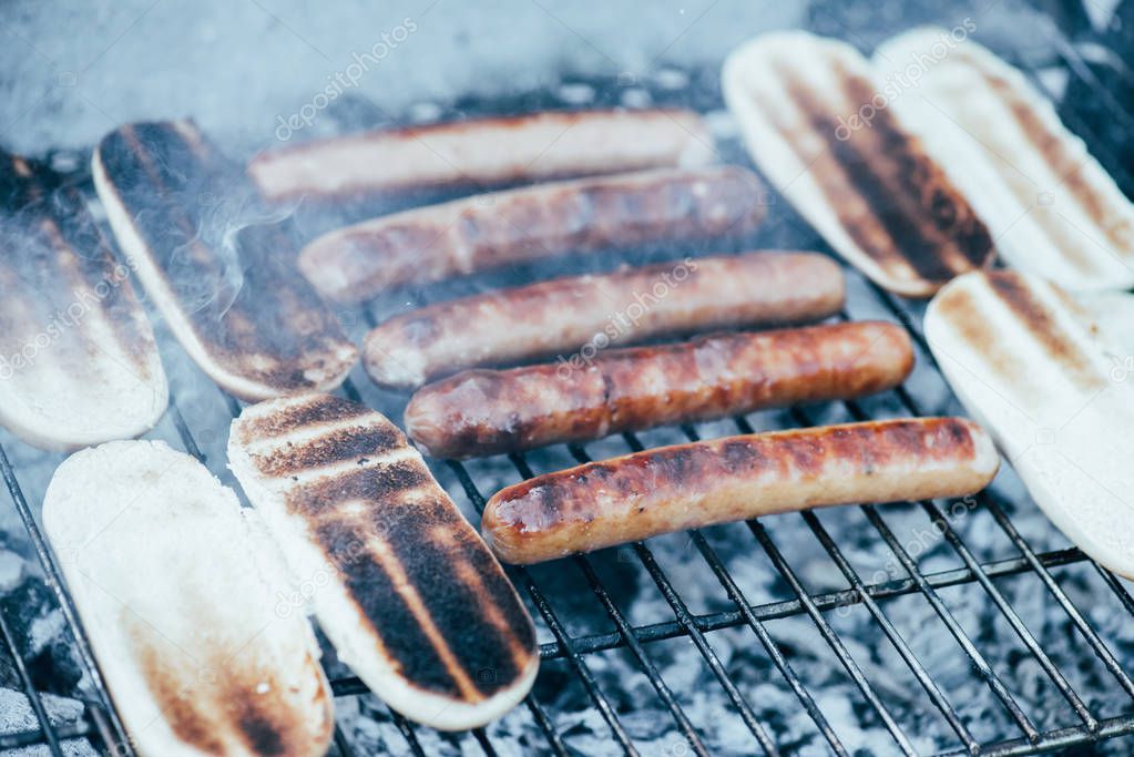 delicious hot dogs grilling with smoke on barbecue grill grade 