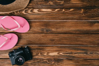 top view of pink flip flops, straw hat and retro film camera on wooden surface clipart