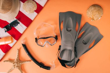 top view of summer accessories and diving equipment on orange background with seashells clipart