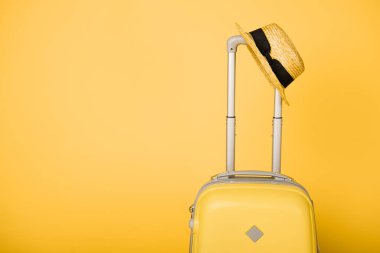 parlak sarı seyahat çantası ve saman şapka sarı zemin üzerine
